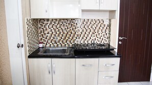A kitchen with a tiled backsplash, a stove, and cabinets. - Pool View 2BR Mutiara Bekasi Apartment (Bekasi)