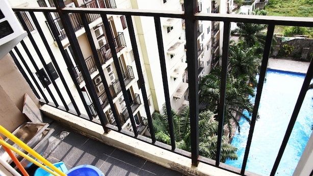 A balcony with a view of a swimming pool and surrounding greenery. - Pool View 2BR Mutiara Bekasi Apartment (Bekasi)