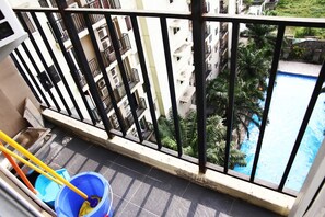 A balcony with a view of a swimming pool and surrounding greenery. - Pool View 2BR Mutiara Bekasi Apartment (Bekasi)
