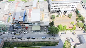 An aerial view of a commercial area with multiple buildings, a parking lot, and a few vehicles. - Cozy Studio Apartment at Elpis Residence (Jakarta)