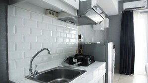A compact kitchen with a stainless steel sink, a black toaster, and a white tiled backsplash. - Modern and Comfortable Studio Apartment Springlake Summarecon near Summarecon (Bekasi)