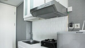 A modern kitchen with white cabinetry, a stainless steel range hood, and a built-in gas stove. - Modern and Comfortable Studio Apartment Springlake Summarecon near Summarecon (Bekasi)