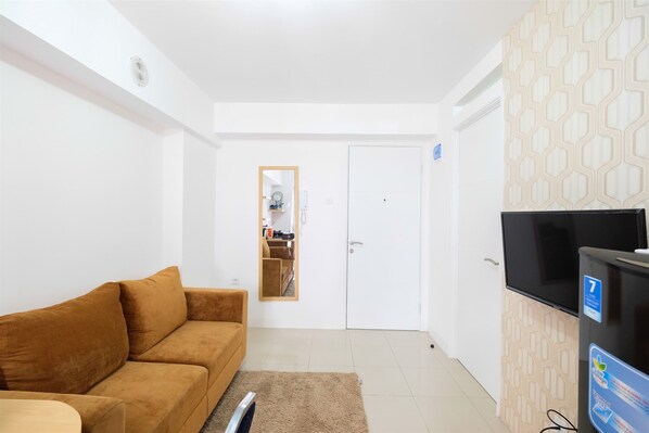 A living room with a brown sofa, a TV, and a patterned cabinet.