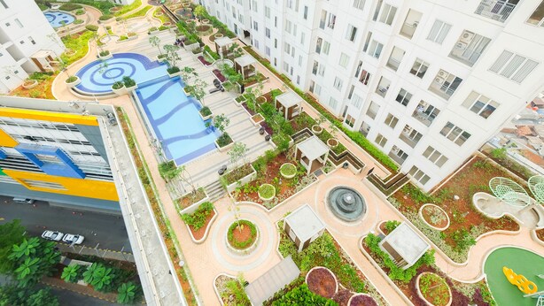 A high-rise residential building with a rooftop garden, swimming pool, and a pedestrian walkway. - Cozy 2BR Bassura City Apartment (Jakarta)