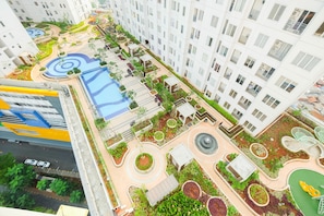 A high-rise residential building with a rooftop garden, swimming pool, and a pedestrian walkway.