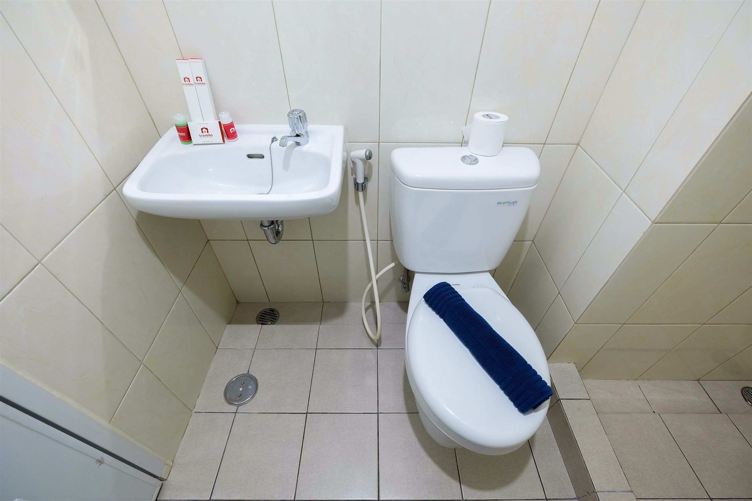 A bathroom with a white sink, toilet, and a blue towel on the toilet seat.