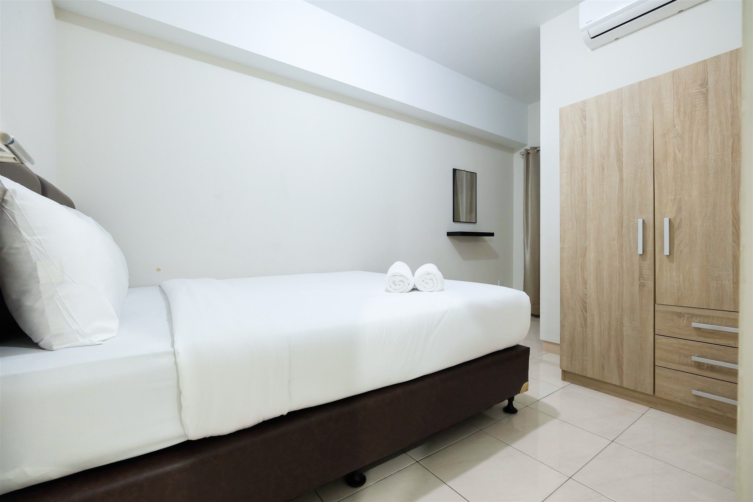 Une chambre à coucher comprenant un lit, une armoire et un climatiseur fixé au mur.