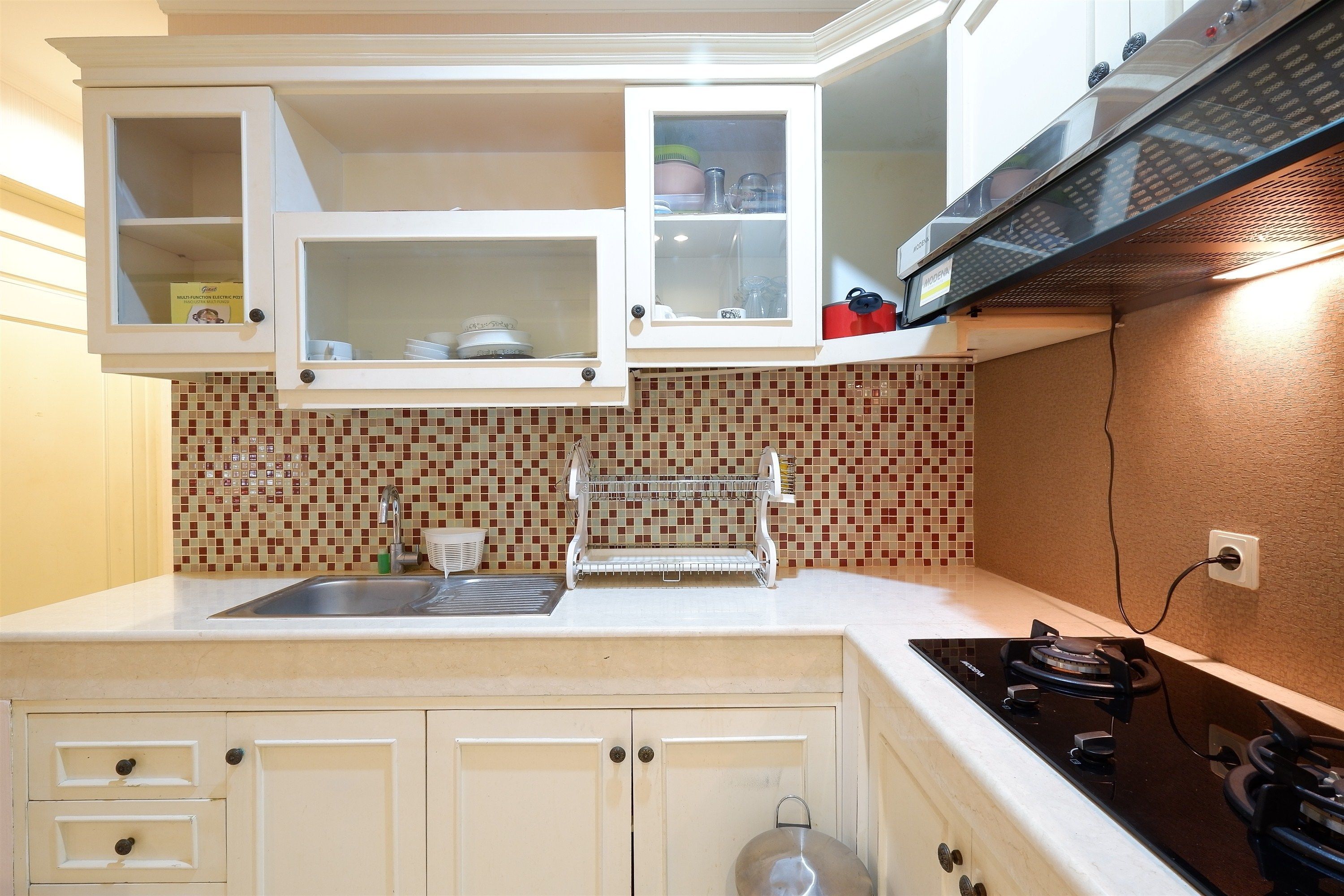 A kitchen with white cabinets, a tiled backsplash, a stainless steel sink, and a gas stove.