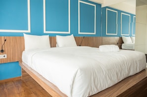 A modern hotel room with a large bed, wooden headboard, and blue accent walls. - Spacious Studio Room near Cihampelas Walk at Galeri Ciumbuleuit 3 Apartment (Bandung)