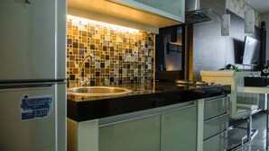 A modern kitchen with a black countertop, stainless steel sink, and a tiled backsplash.