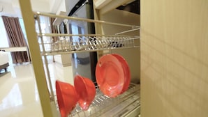 A kitchen with a dishwasher and a drying rack with red plates. - Modern Studio The H Residence near MT Haryono (Jakarta)