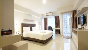 A hotel room with a large bed, a desk with a computer, a TV, and a window with curtains. - Modern Studio The H Residence near MT Haryono (Jakarta)