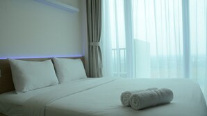 Een hotelkamer met een opgemaakt bed, uitzicht door het raam en een gordijn.
