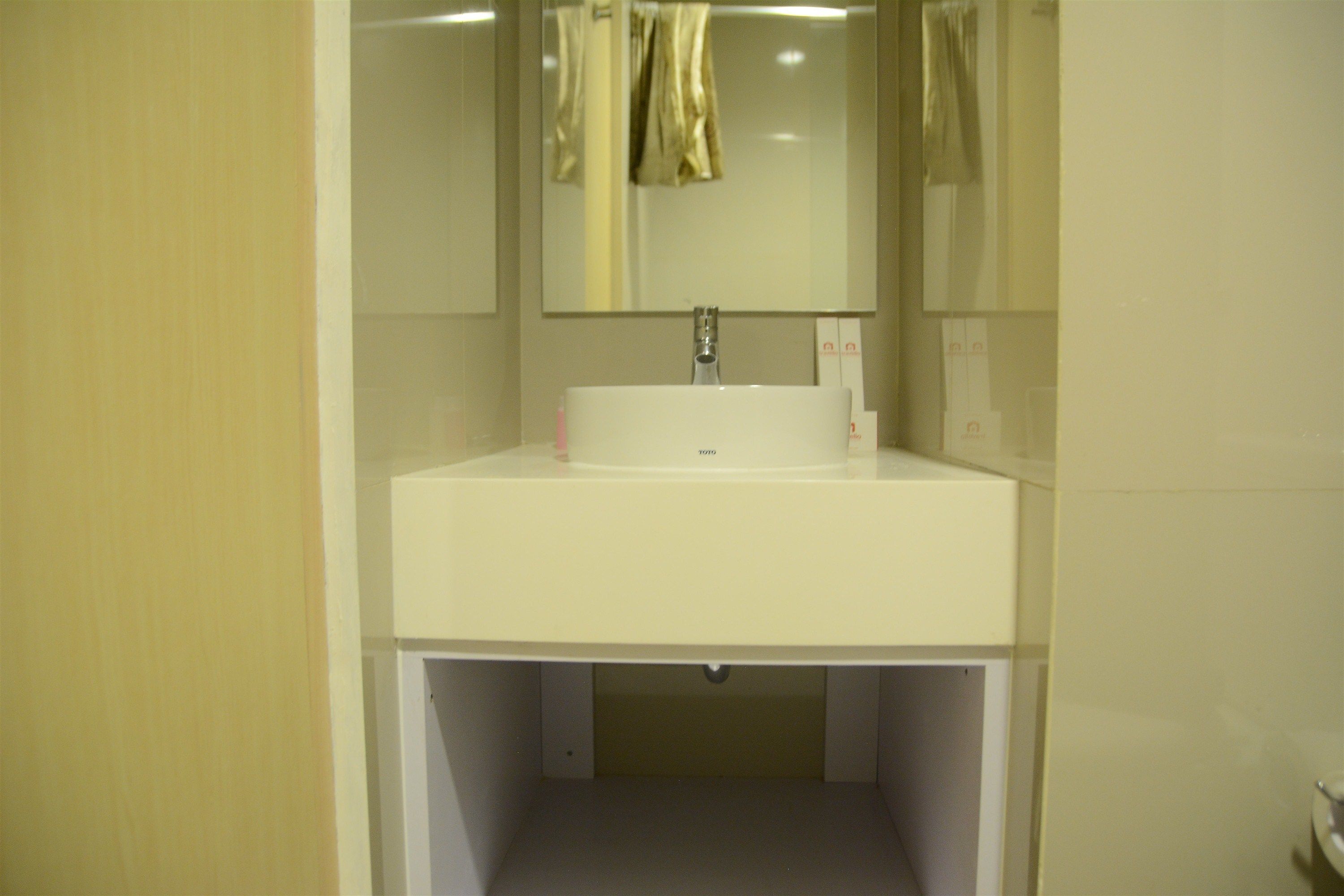 Un baño con un lavabo blanco, un espejo y una toalla colgada en la pared.