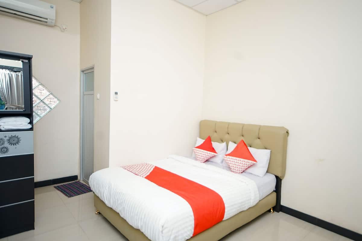 A hotel room with a bed, a wardrobe, and an air conditioning unit.