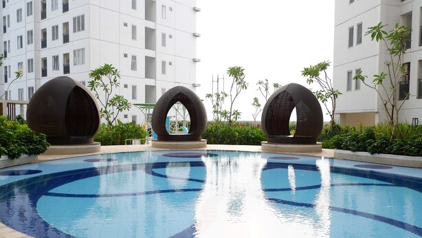 A swimming pool with three large spherical structures in the center, surrounded by greenery and modern buildings in the background. - Spacious 2BR Apartment Connected to Bassura City Mall (Jakarta)