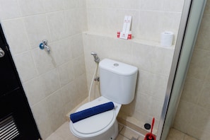 A small, clean bathroom with a toilet, a blue towel, a toilet paper roll, and a hand dryer. - Exclusive 1BR Apartment The Wave Kuningan near Epicentrum (Jakarta)