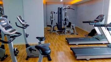 Un gimnasio con cintas de correr, elípticas y equipo de pesas.