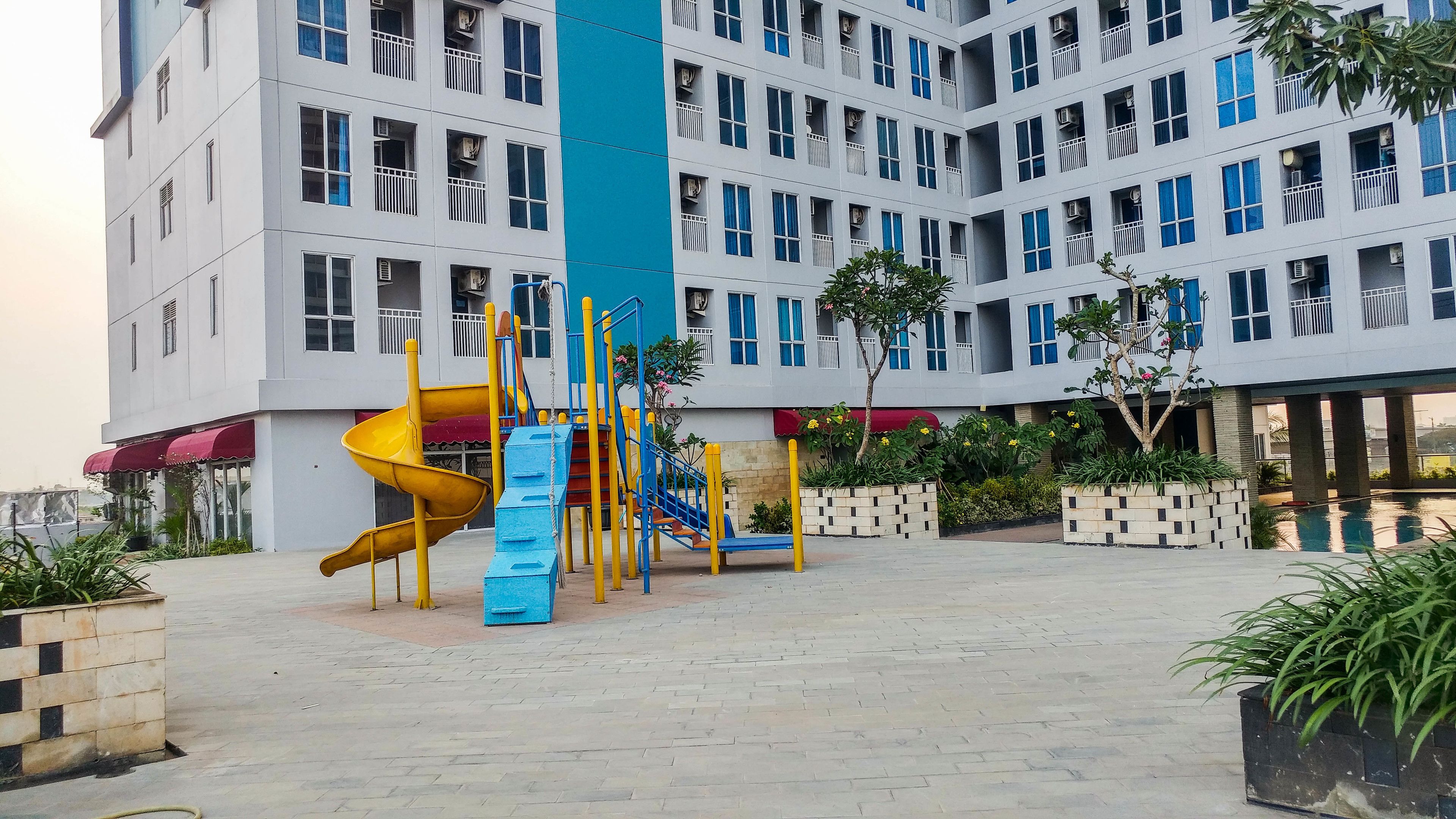 Ein Spielplatz mit Rutschen und Klettergerüsten vor einem mehrstöckigen Gebäude mit Balkonen.