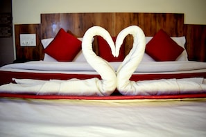 A bed with a heart-shaped towel arrangement and red pillows. - Hotel Shree Pratham Milan (Nathdwara)