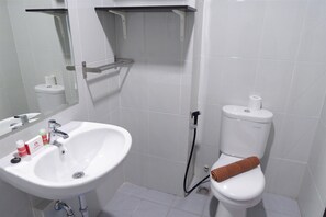 A bathroom with a white sink, a toilet, and a shower area. - Comfy Studio Casa De Parco Apartment (Pagedangan)