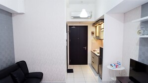 A compact living space with a black sofa, a small TV, a kitchenette, and a dining table with a few items.