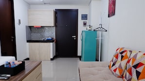 A compact living space with a kitchenette, a sofa, and a bed. - Close to Pool Studio Apartment Sky Terrace at Daan Mogot Baru (Jakarta)