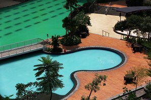 Une piscine dotée d’une terrasse en bois, entourée de palmiers et agrémentée d’un espace salon abrité.