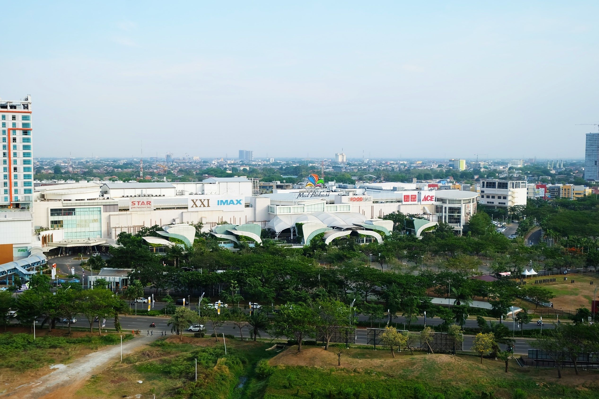 A commercial area with IMAX and Star cinemas, a tall building, and a mix of greenery and urban structures.