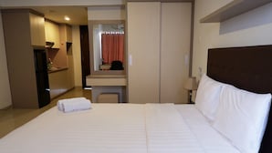 Una habitación de hotel con una cama grande, un escritorio con una silla, un espejo y un armario.