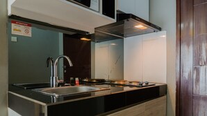 Una cocina moderna con un lavamanos de acero inoxidable, encimera negra y armarios de madera.