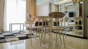 Una sala moderna con un sofá, una mesa de comedor con sillas, una mesita blanca y un ventanal con cortinas.