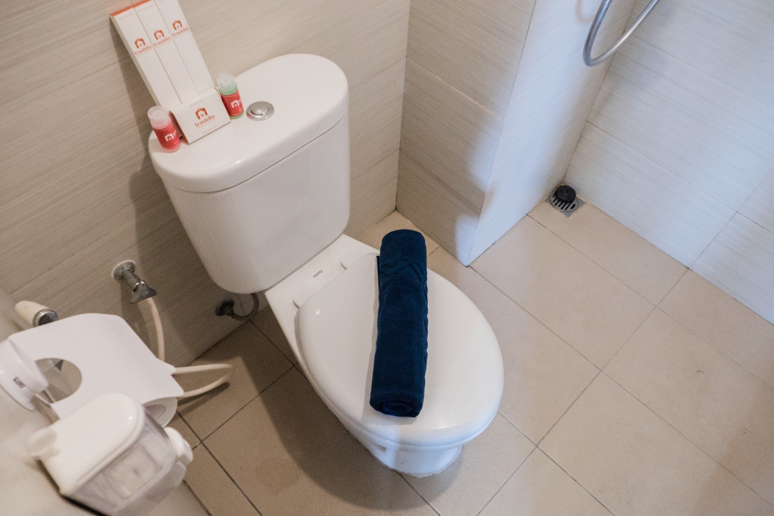 A white toilet with a blue towel on the seat, a bidet, and a toilet paper holder.