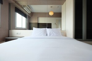 Habitación de hotel moderna con una cama grande, una mesita de noche, un espejo y una ventana.