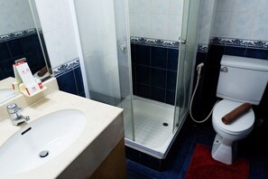 Une salle de bain équipée d’un lavabo, de toilettes et d’une douche à parois de verre.