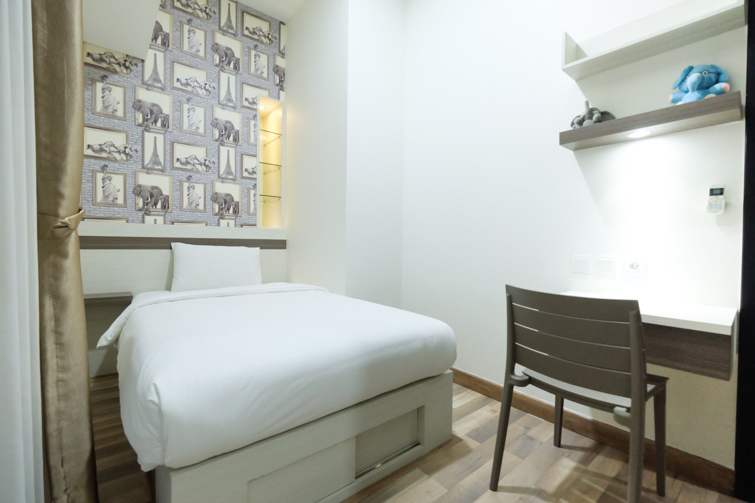 Une chambre à coucher avec un lit, une chaise, une étagère avec un jouet et un mur orné de tableaux encadrés.