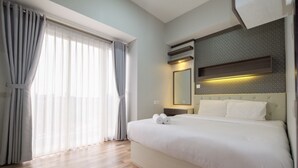 Una habitación de hotel moderna con una cama grande, una mesita de noche, un espejo y una ventana con cortinas.
