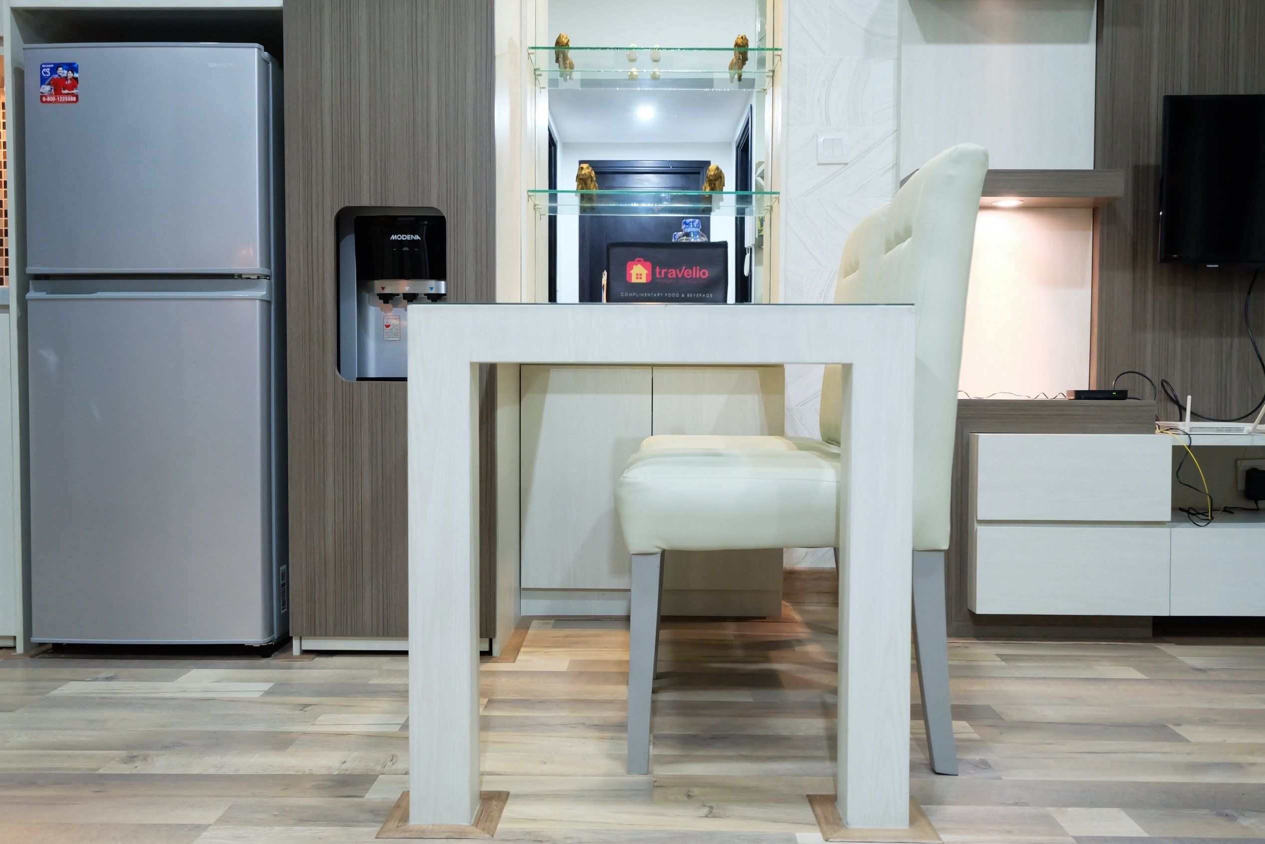 Una cocina moderna con refrigerador empotrado, dispensador de agua y repisa de vidrio sobre el lavamanos.