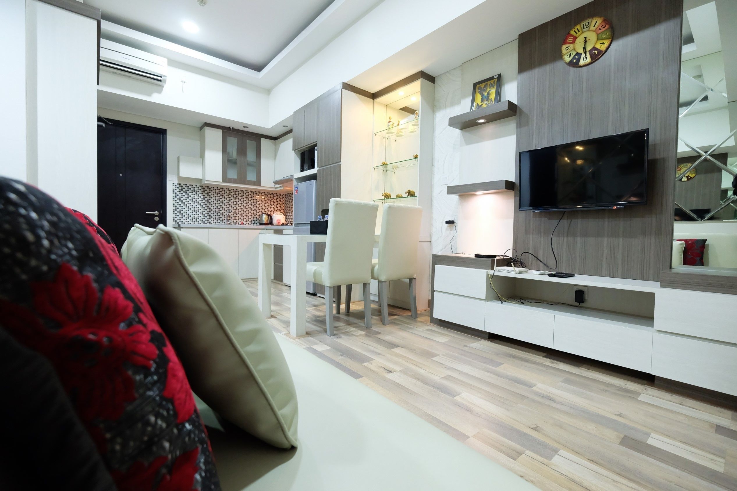 Ein modernes Wohnzimmer mit einer Couch, einem Fernseher und einem Essbereich mit Stühlen.