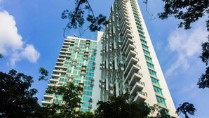 A tall, modern building with multiple balconies and a mix of glass and solid facade elements.