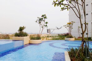 Relax by the rooftop pool surrounded by lush greenery and city views.