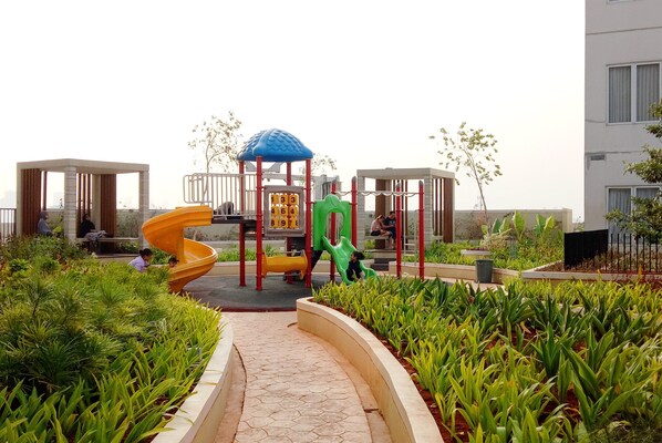 Children can play and explore amidst lush greenery and modern play structures.