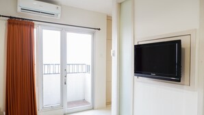 Quarto com porta de vidro deslizante, televisão de tela plana montada e ar-condicionado instalado no teto.