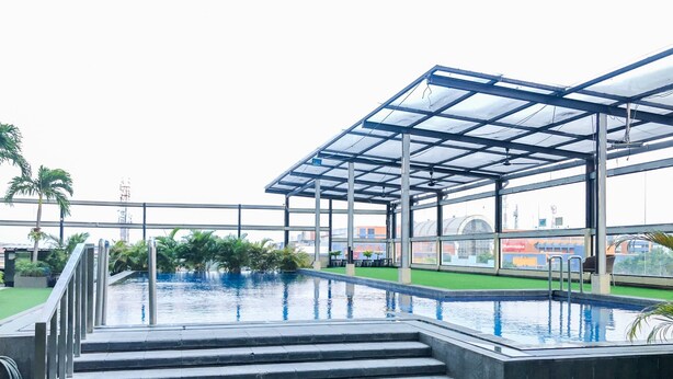 Uma piscina no terraço com água azul cristalina, cercada por uma estrutura de vidro e escadas que descem até a piscina.