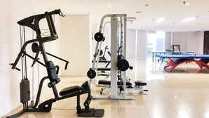 Uma academia com equipamentos de ginástica, mesa de bilhar e um espaço interior amplo e iluminado.