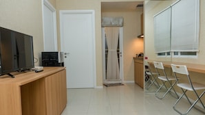 A small kitchenette with a TV, coffee maker, and a door leading to a bathroom. - Minimalist 2BR Apartment at Parahyangan Residence (Bandung)