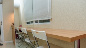 A dining area with a long wooden table and four white chairs. - Minimalist 2BR Apartment at Parahyangan Residence (Bandung)