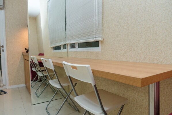 Un espace repas avec une longue table en bois et quatre chaises blanches.