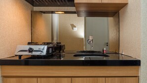 A kitchen with a gas stove, a microwave, and a stainless steel sink. - Minimalist 2BR Apartment at Parahyangan Residence (Bandung)