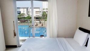 Une chambre d’hôtel avec un lit, une vue sur une piscine et un balcon.